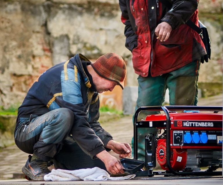 gambar genset yang sedang di operasi oleh 2 orang